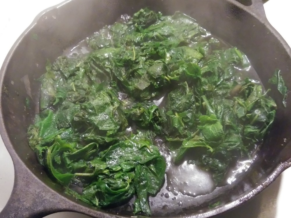 Stinging nettles sauted in a cast iron skillet.